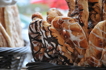 Pastry drizzled in chocolate and icing in a wicker basket in a store window display.