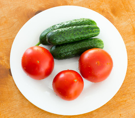 fresh tomato and cucumber in a plate on a brown table