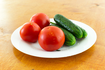 fresh tomato and cucumber in a plate on a brown table