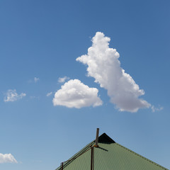 Blue sky with clouds over the roof of the house