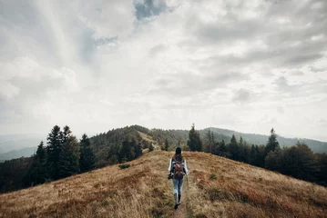 Foto op Canvas hipster traveler with backpack walking on top of mountains. wanderlust and travel concept with space for text. stylish woman hiking. atmospheric epic moment © sonyachny