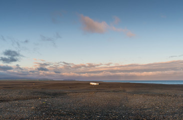 The evening sun lights up the Sólheimasandur plane wreck, which lies on a black sand beach ib Iceland.