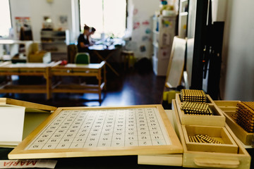 Table and shelving with montessori material, colored items and wooden cylinders to study geometry in the classroom.