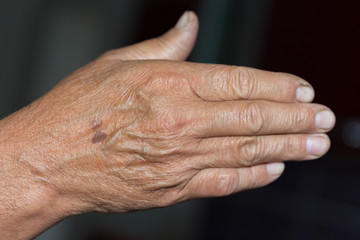 Fototapeta premium wrinkled hand of an old man on a black background