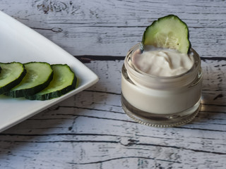 Cucumber face cream on white wooden background