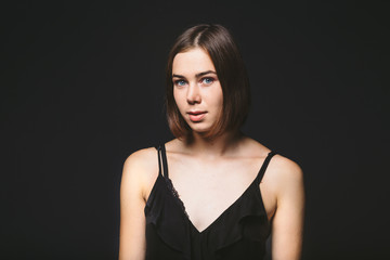 Fototapeta premium Portrait of a beautiful young Caucasian Caucasian woman 20 years old model with blue eyes natural make-up of hair on shoulder dancing hands posing on black isolated background in black lingerie