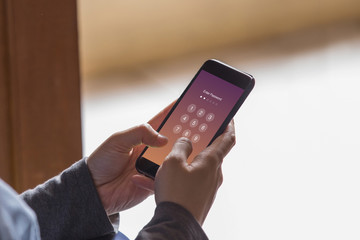 Enter Passcode concept. Hands holding smartphone while entering the passcode.