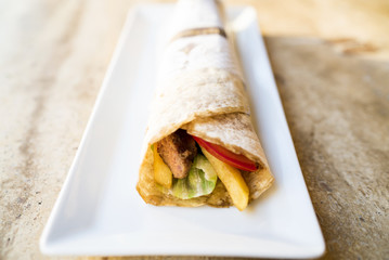 Tasty turkish kebab in tortilla wrap serving on white plate