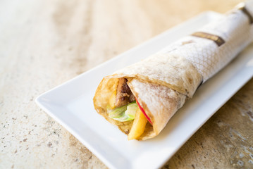 Tasty turkish kebab in tortilla wrap serving on white plate