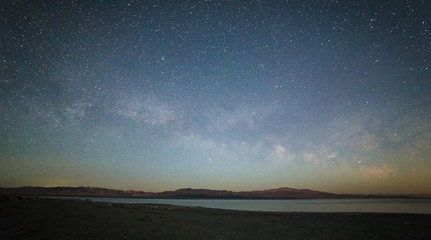 Milky Way above horizon across the lake with mountains range in the background