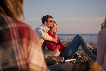 Couple enjoying with friends at sunset on the beach