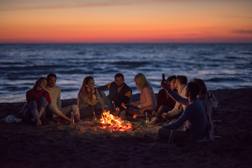 a group of friends enjoying bonfire on beach
