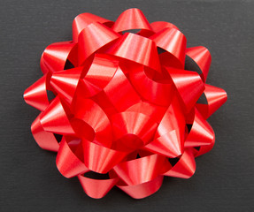 Black gift box on a dark contrasted background, decorated with a red color bow, creating a romantic atmosphere. Typically used for birthday, anniversary presents, gift cards, post cards.