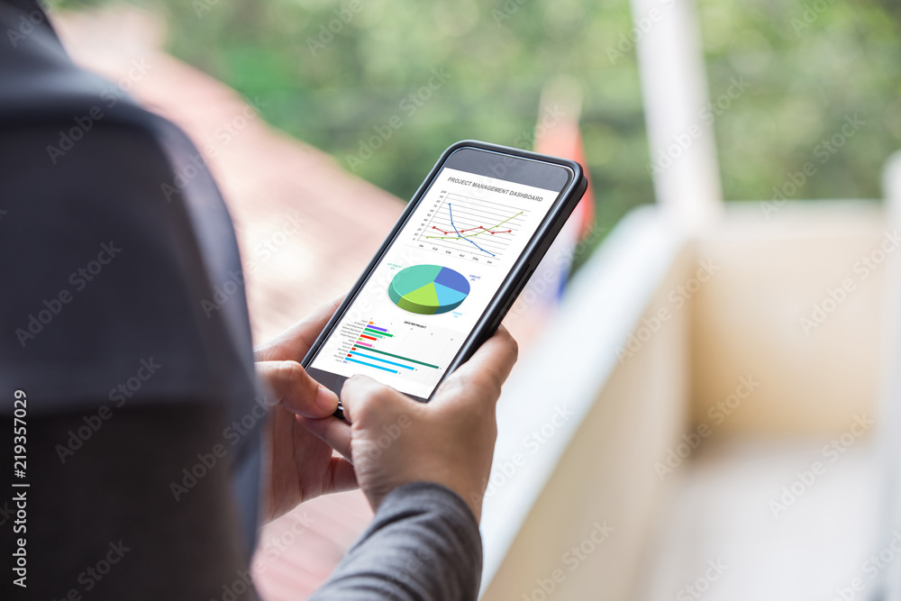 Poster project management dashboard concept. woman hand holding phone with excel project dashboard on scree
