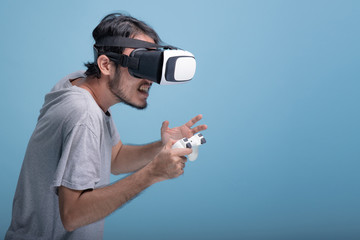 Young bearded man playing VR game in blue background.