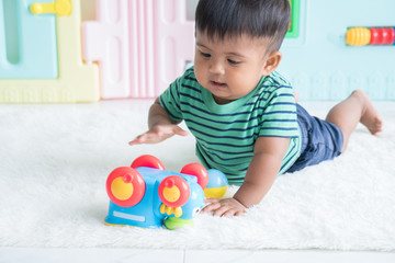 Cute little baby boy lying on the floor and play toy car