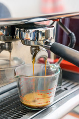 Close-up of espresso pouring from coffee machine. Professional coffee brewing