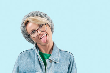Beautiful positive girl shows tongue on blue background
