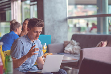 Young skilled male freelancer starting working day early in morning drinking coffee to wake up