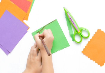 Children's hands cut out colored paper with figured scissors. Activities for children, leisure.