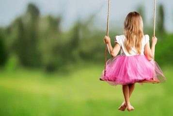 Little child blond girl having fun on a swing