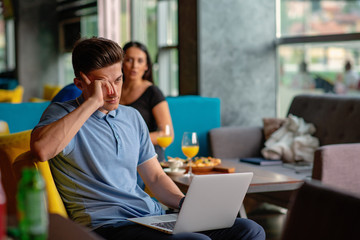 Young skilled male freelancer starting working day early in morning drinking coffee to wake up