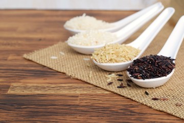rice varities, riceberry, jasmine rice in white spoon on wood sack background