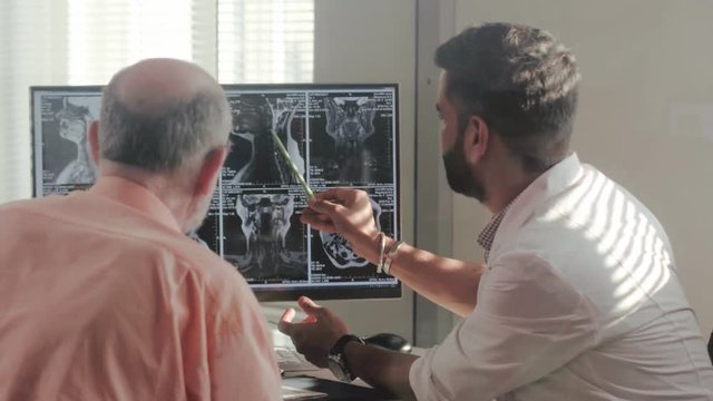 Doctor of research center shows the patient x-ray images on computer and tells about results of treatment