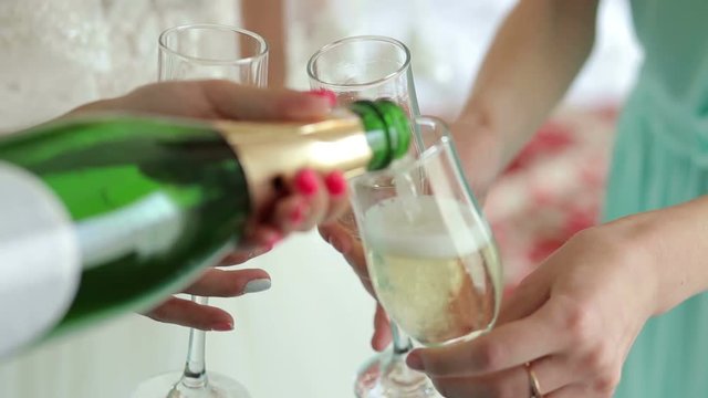 Close-up of the girl poured champagne into glasses at a bachelorette party. The bride and her friends drinking champagne at the wedding, close-up.