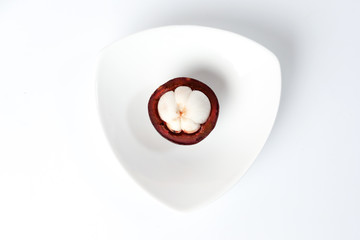 Purple mangosteen fruit pealed half on white hart shape plate background