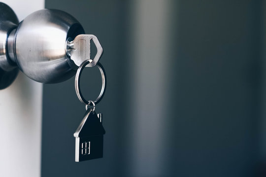 Property Concept, Home key with metal house keychain in keyhole - Powered by Adobe