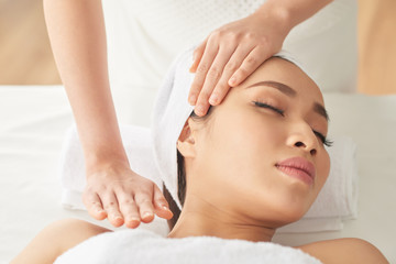 Fototapeta na wymiar Pretty young Asian woman enjoying massage in spa salon