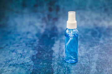 Spray bottle with blue liquid inside on blue grunge backdrop in selective focus