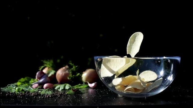 Chips fall into a glass plate, on the side are the remaining ingredients, onions, garlic, spices. Futa for advertising chips.