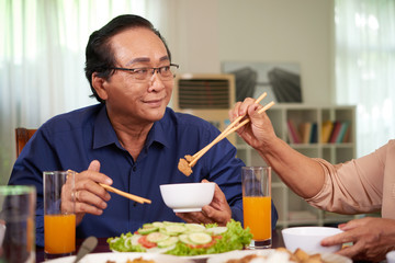 Fototapeta na wymiar Senior Vietnamese man having tasty dinner at home with his wife