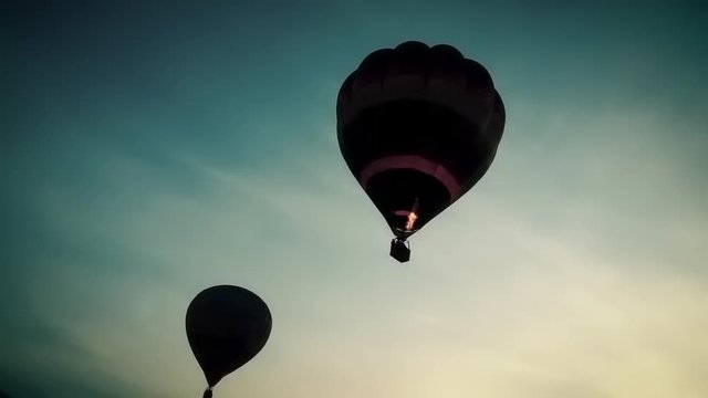 Silhouette of two hot air balloon float across the sky in the morning.