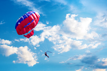 Woman are flying in the blue sky using a colorful parachute. Parasailing vacation concept.