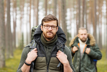 Man with a backpack and beard and his friend hiking in forest in autumn.