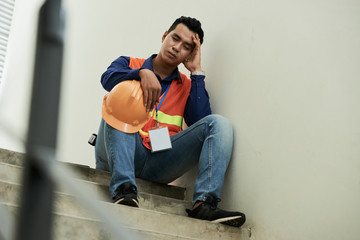 Stressed tired construction worker taking nap on stairs