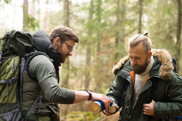 Fototapeta premium Mężczyzna z plecakiem i brodą oraz jego przyjaciel wędrują po lesie jesienią.