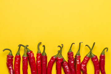 Top with green tails Red hot Chilean pepper on a yellow backgrou