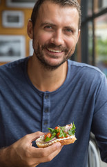 Young happy man eating his lunch. Handsome man enjoying his organic food. Healthy eating