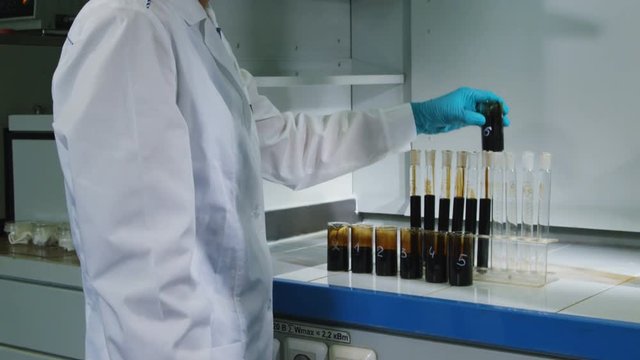 motion past lab assistant filling tubes with oil at workplace