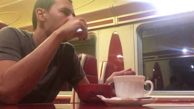 man at night eating soup in the train restaurant railway cat drinks coffee. man on the train concept journey travel lifestyle railway