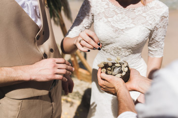 Priest holding wedding rings in handmade wicker nest on ceremony before oath.