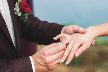 Groom wearing ring on bride's hand on wedding ceremony close-up
