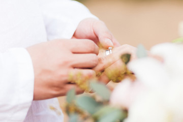 Groom wearing ring on bride's hand on wedding ceremony close-up