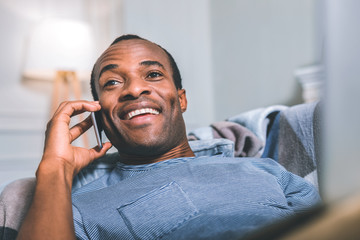 Surprising news. Surprised attractive man speaking on the phone while laying on the bed