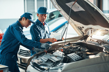 Mechanics using laptop when checking car in garage