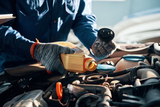 Hands of mechanic pouring a bottle of oil in car engine
